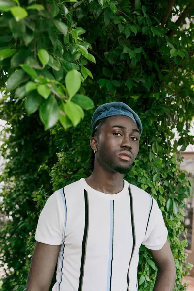 Sophisticated man poses elegantly in front of a lush tree. — Stock Photo