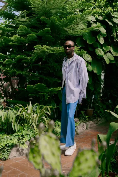 A handsome African American man in sophisticated attire stands gracefully in front of a lush green forest. — Stock Photo