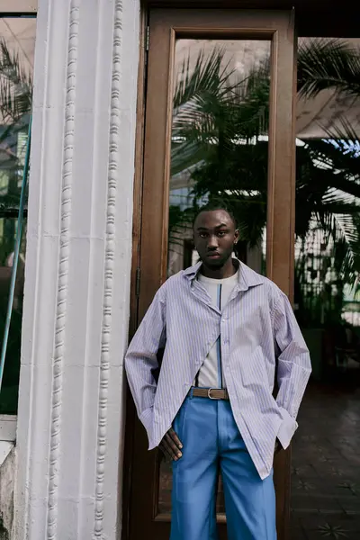 Um homem afro-americano sofisticado está em uma porta do jardim com as mãos nos bolsos. — Fotografia de Stock