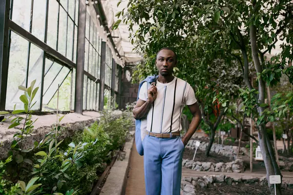 Складний афроамериканський чоловік позує модно в пишному тепличному саду. — стокове фото