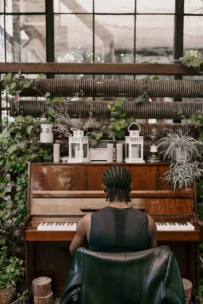 A man sits at a piano, playing in greenhouse. — Stock Photo