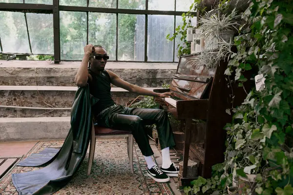 A sophisticated man sits next to a grand piano in a vibrant green garden. — Stock Photo