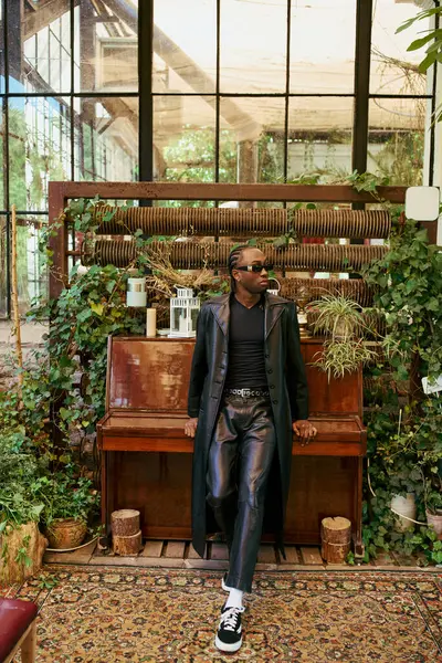 Ein bulliger afroamerikanischer Mann sitzt auf einer Bank vor einem Klavier in einem lebhaften Garten. — Stock Photo