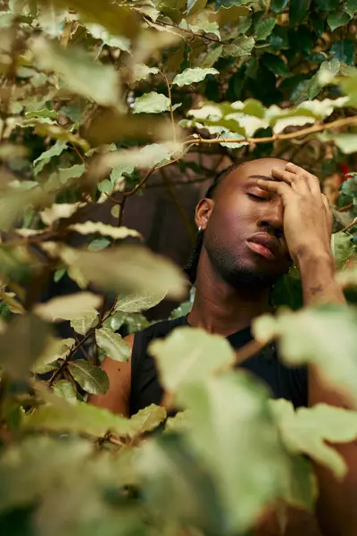 Handsome African American man in dapper style sitting in a tree with head in hands. — Stock Photo
