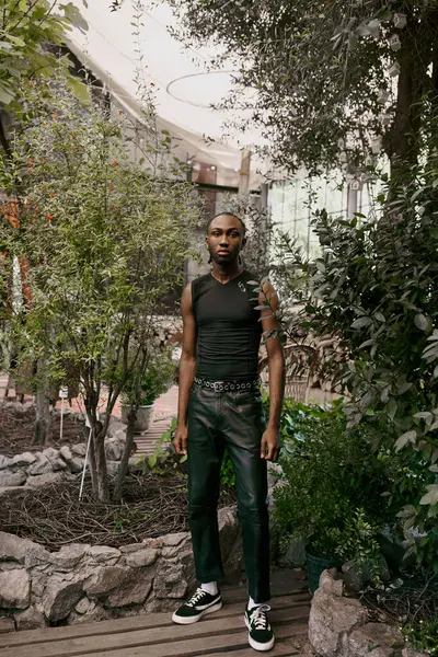 A handsome African American man with sophisticated dapper style standing in a vivid green garden. — Stock Photo