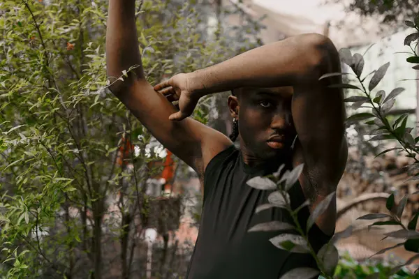 A sophisticated African American man stands by a tree, hands on head. — Stock Photo