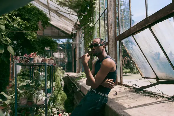 Stylish African American man in vibrant greenhouse. — Stock Photo