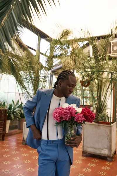 Sophisticated African American man in blue suit holding a bunch of colorful flowers in a vibrant green garden. — Stock Photo