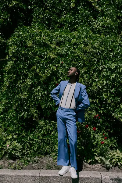 A stylish man in a blue suit stands confidently on a urban sidewalk. — Stock Photo