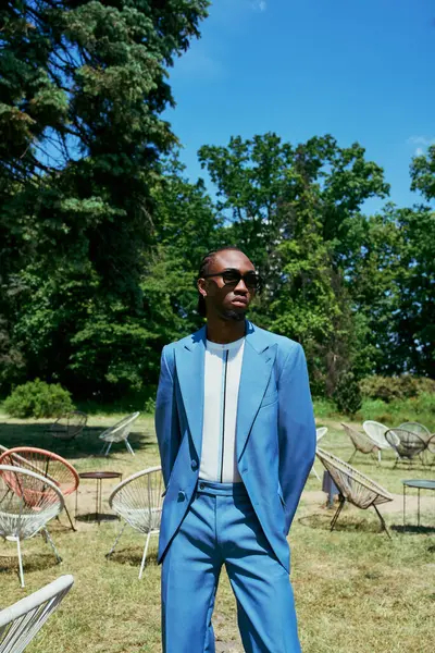 Um homem afro-americano sofisticado de fato azul está graciosamente num campo vibrante.. — Fotografia de Stock