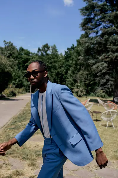 Стильний афроамериканський чоловік у блакитному костюмі впевнено ходить уздовж тротуару. — стокове фото