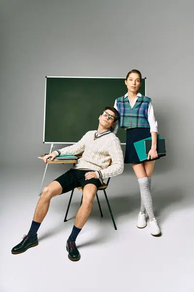 Un elegante estudiante masculino y femenino posando frente a una pizarra en la universidad. - foto de stock