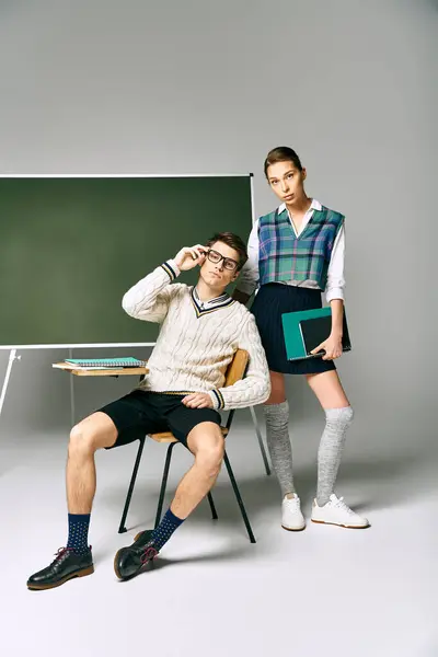 Stylish man and woman pose elegantly in front of green chalkboard. — Stock Photo