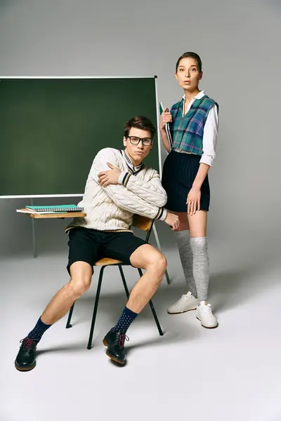 Elegante hombre y mujer posando frente a un tablero verde en la universidad. — Stock Photo