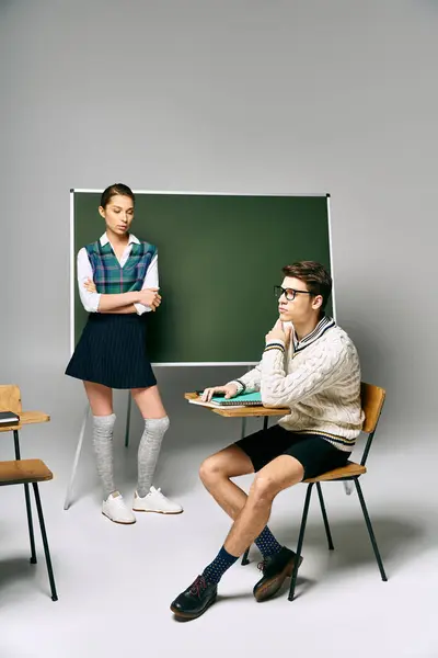 Hombre guapo y mujer hermosa sentado en frente de pizarra en la universidad. — Stock Photo