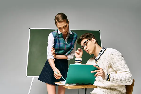 Elégants étudiants masculins et féminins assis devant un tableau vert dans un cadre universitaire. — Photo de stock
