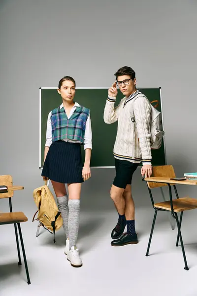 Elegant man and woman posing in front of a green board at college. — Stock Photo