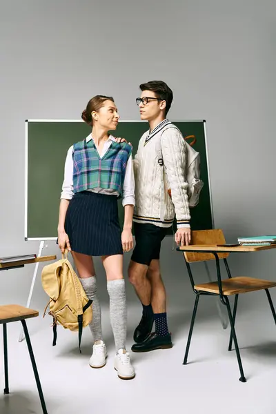 Elegant man and woman posing in front of a green chalkboard. — Stock Photo