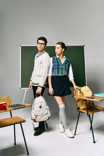 Two students, male and female, stand elegantly before the green college chalkboard. — Stock Photo
