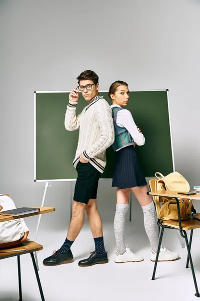 Elegant man and woman standing in front of college green board. — Stock Photo
