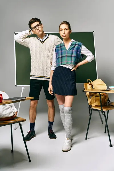 Stylish young man and woman posing in front of a green board in college. — Stock Photo