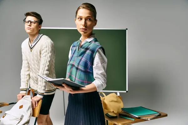 Un bel homme et une belle femme debout devant un tableau vert à l'université. — Photo de stock