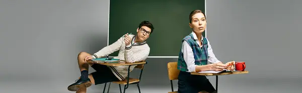 Two elegant students sit at a desk in a college classroom, engaging with a green board. — Stock Photo