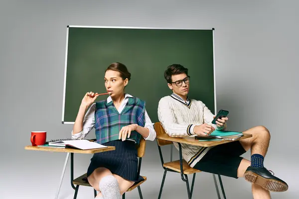 Стильний чоловік і жінка сидять за столом перед зеленою дошкою. — Stock Photo