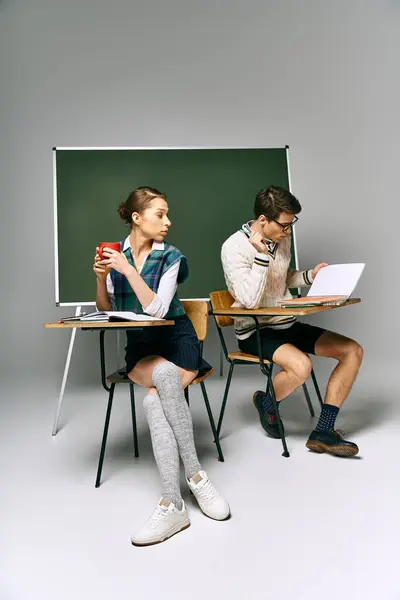 Homem e mulher elegantes sentados na mesa, contemplando na frente do quadro verde. — Fotografia de Stock