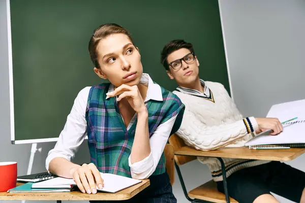 Homem e mulher elegantes sentados na frente do quadro verde. — Fotografia de Stock