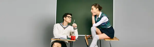 Elegante Studentinnen und Studenten sitzen im College vor einer grünen Tafel. — Stockfoto