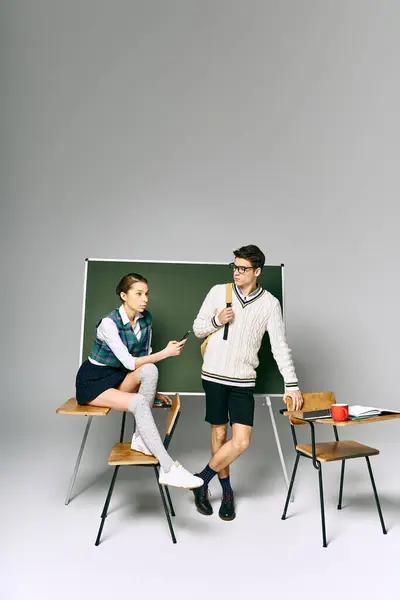 Elegant man and woman pose in front of green board in college. — Stock Photo