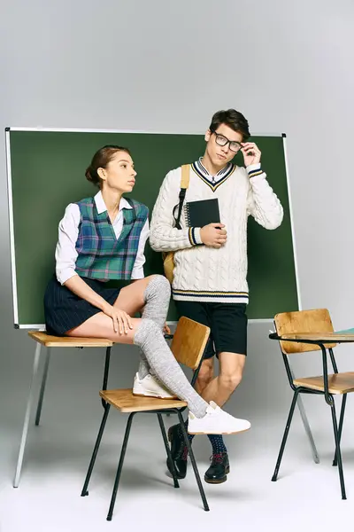 Elegante uomo e donna in piedi accanto a bordo verde nel college. — Foto stock