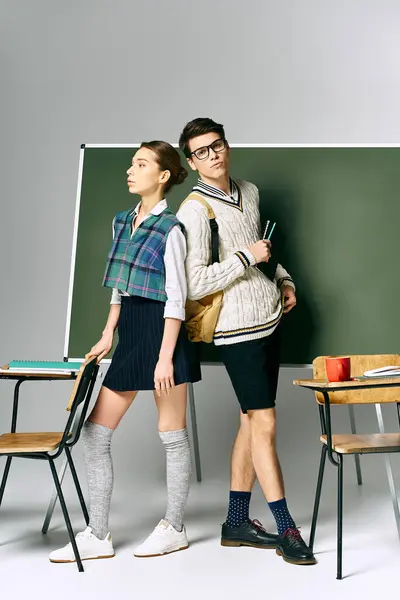 Ein schöner Mann und eine schöne Frau stehen selbstbewusst vor einer grünen Tafel. — Stockfoto