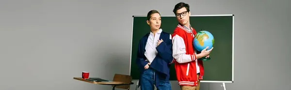 Two students standing in front of a green board in a classroom setting. — Stock Photo