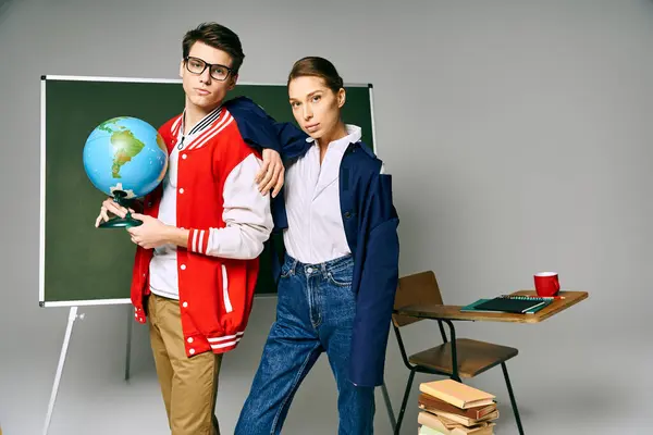 A male and female students stand in front of a chalkboard in a college classroom. — Stock Photo
