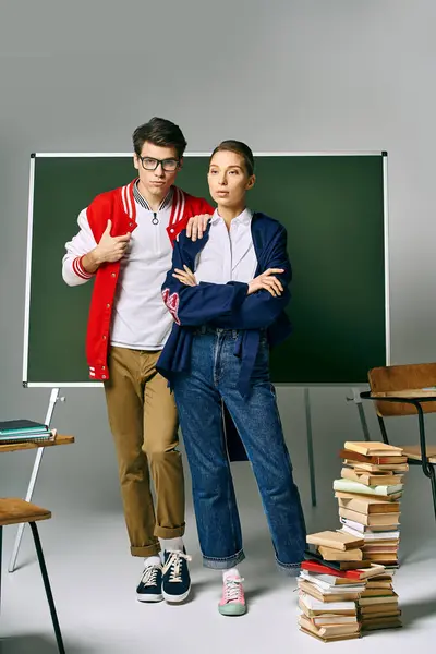 Male and female students pose confidently in front of a green board. — Stock Photo