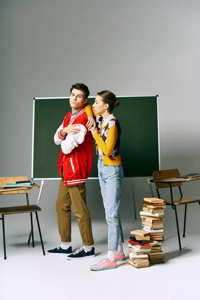 Zwei attraktive Studenten in Freizeitkleidung stehen vor einer grünen Tafel in einem College-Klassenzimmer. — Stockfoto