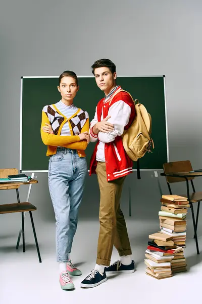 Young male and female students standing confidently in front of a green board in a college classroom. — Stock Photo