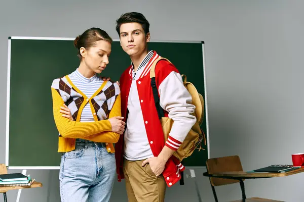 Young male and female students standing confidently in front of a chalkboard. — Stock Photo