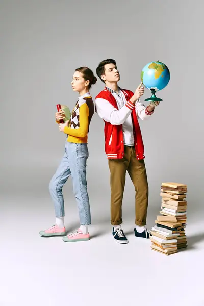A man and a woman stand beside a tall stack of books in a college classroom. — Stock Photo