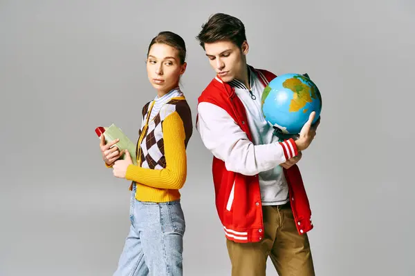 Young male and female students holding a globe in a classroom setting. — Stock Photo