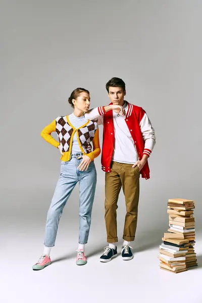 Young male and female students embracing while posing next to stack of books in college classroom. — Stock Photo