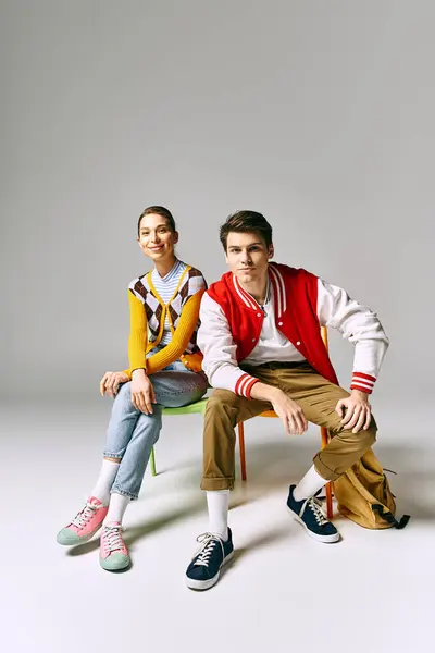 A stylish male and female students sit gracefully on a colorful chair. — Stock Photo