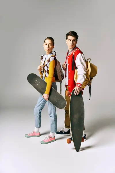Deux jeunes tiennent des planches à roulettes sur fond blanc. — Photo de stock