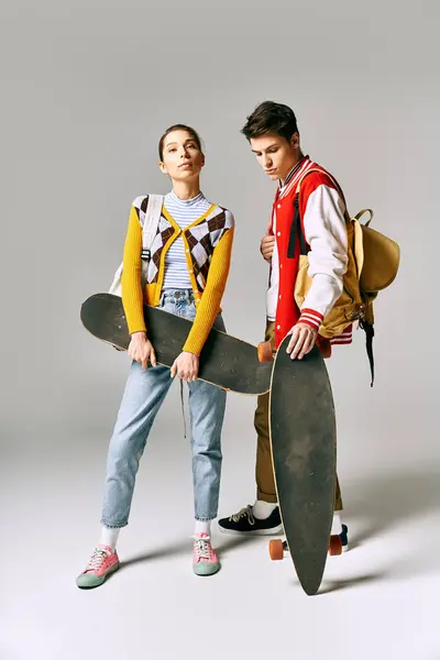 Stylish male and female students posing with skateboards in front of a white background. — Stock Photo