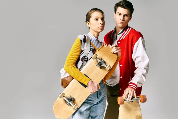 Young male and female students proudly hold skateboards in a college setting. — Stock Photo