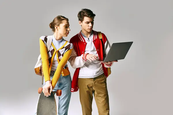Young male and female students stand together, holding a laptop in a college classroom. — Stock Photo