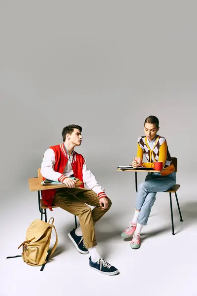 Young male and female students in casual attire discussing at a desk in a college classroom. — Stock Photo