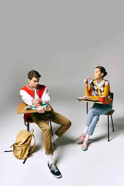 A man and a woman sitting at desks in a studio, engrossed in their creative work. — Stock Photo